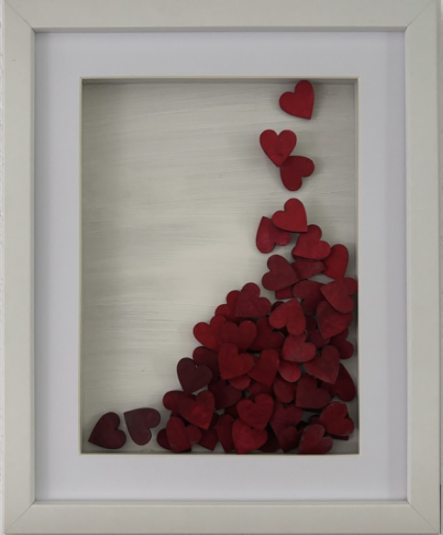 Falling (II) — cascade of red wooden hearts in white shadow-box frame